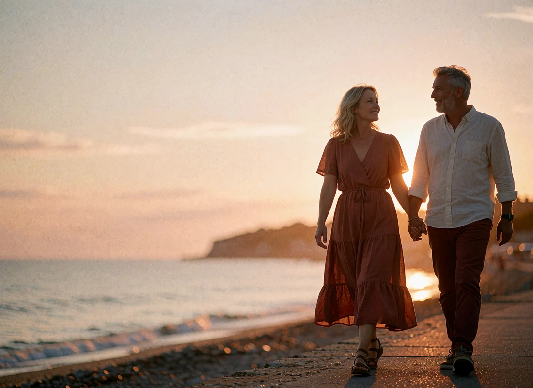 Couple walking together along a seaside promenade at sunset, holding hands
